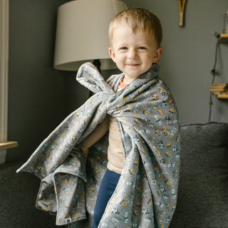 Child on a couch playing with an AdventureUs made minky blanket and lovey.