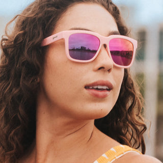 Woman wearing pink goodr sunglasses. These floating sunglasses are the ultimate plus-one for pool parties and I'M ON A BOAT moments. Featuring light blue Tidal G frames and blue reflective water-repellent lenses, you'll look like a paddleboarding pro!