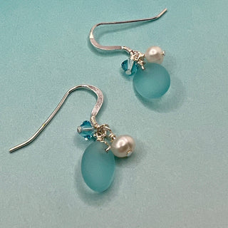 Tumbled matte aqua blue glass creates a soft contrast to the satin finish of Freshwater Pearls.

Sterling silver hooks

Aquamarine blue high quality Crystal

Local Artist&nbsp;