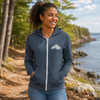Woman wearing a blue hoodie with a Lake Superior logo, standing by a body of water with trees in the background