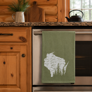 Green towel with a Wisconsin forest design hanging on a kitchen appliance