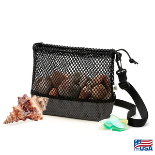 Black AdventureUs mesh collecting bag with carrying strap for agate hunting, rock collecting, mushroom foraging, and beachcombing. Filled with rocks with nature items around for featured suggested use.