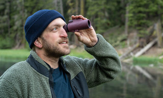 Man using binoculars in a forest setting