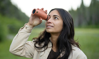 Woman using a red binoculars in a forest setting