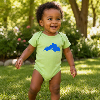 Child wearing a green onesie with a blue graphic outdoors