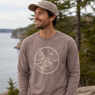 Man wearing a shiitake colored Lake Superior long sleeve shirt with AdventureUs Washburn WI artwork by the lake.