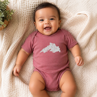 Baby wearing a pink onesie with a white design, lying on a textured beige blanket.