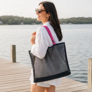 Woman with a black mesh tote bag on a dock by a lake