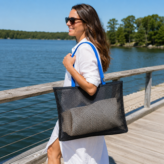 Woman holding a black mesh tote bag by a lake