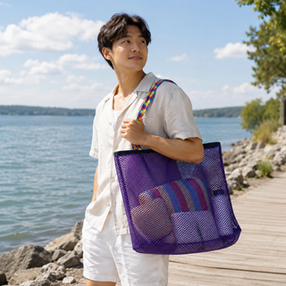 Man holding a purple mesh beach bag by a lakeside