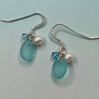 Tumbled matte aqua blue glass creates a soft contrast to the satin finish of Freshwater Pearls.

Sterling silver hooks

Aquamarine blue high quality Crystal

Local Artist&nbsp;